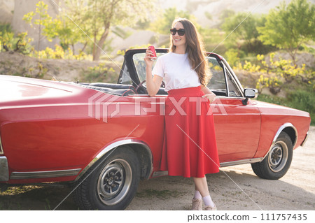 beautiful happy girl in skirt posing near retro car in cappadocia mountains with can of drink beautiful happy girl in skirt posing near retro car in cappadocia mountains with can of drink 111757435