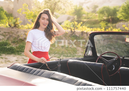 beautiful happy girl in a skirt posing near a retro car in the mountains of cappadocia beautiful happy girl in a skirt posing near a retro car in the mountains of cappadocia 111757440