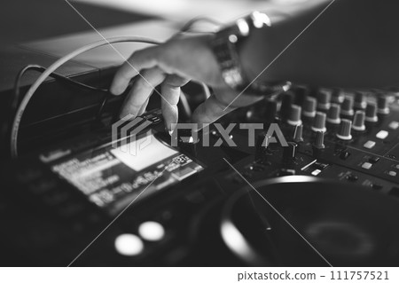 a DJ plays music on a controller at a party a DJ plays music on a controller at a party 111757521