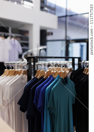 Interior of modern boutique with new collection on racks, fashionable clothes and formal wear in fashion store. Empty clothing showroom in shopping centre with elegant merchandise. Interior of modern boutique with new collection on racks, fashionable clothes and formal wear in fashion store. Empty clothing showroom in shopping centre with elegant merchandise. 111757583