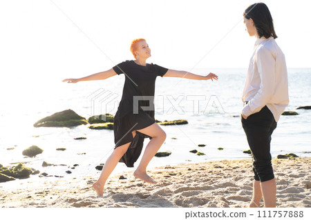 two lovers boy and girl are happy walking and hugging on the sandy beach near the sea. two lovers boy and girl are happy walking and hugging on the sandy beach near the sea. 111757888