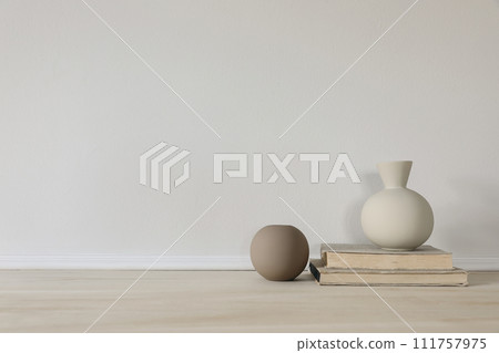 Set of modern brown and beige ceramic vases of geometric shapes on wooden table. Old books. White wall. Abstract trendy artistic background, web banner. Empty copy space. Elegant interior. Set of modern brown and beige ceramic vases of geometric shapes on wooden table. Old books. White wall. Abstract trendy artistic background, web banner. Empty copy space. Elegant interior. 111757975