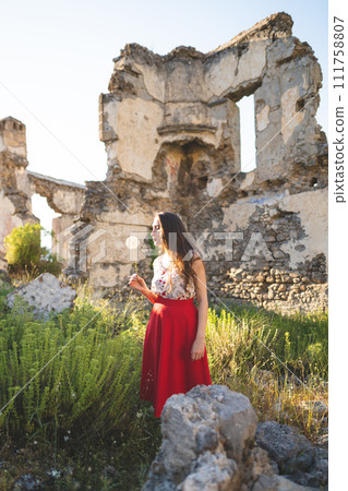 a beautiful girl in a red skirt among the ruins of the old town a beautiful girl in a red skirt among the ruins of the old town 111758807