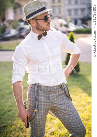 handsome presenter and showman in a stylish suit and hat with a microphone  poses with the best emotions and acrobatic tricks 111758808