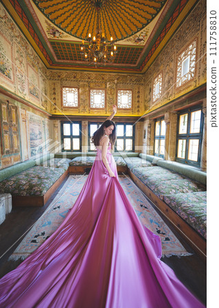 a beautiful girl in a long pink dress poses in a room with a traditional Turkish interior 111758810