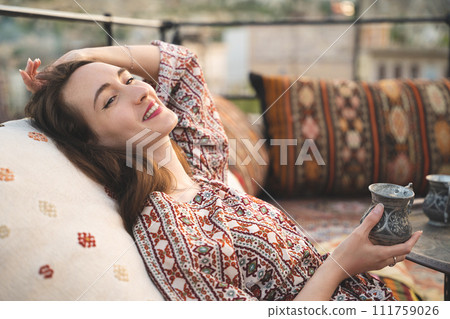 beautiful girl is relaxing with a cup of tea on the sofa in Turkish style and interior beautiful girl is relaxing with a cup of tea on the sofa in Turkish style and interior 111759026