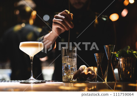 the bartender prepares a beautiful alcoholic cocktail at the bar counter 111759064