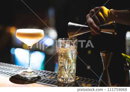 the bartender prepares a beautiful alcoholic cocktail at the bar counter 111759068
