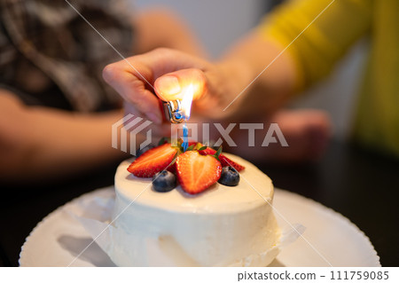 decorated birthday fruit cake lighting a candle 111759085