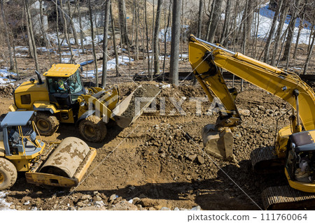 Construction excavator digs trenches at construction site during earthmoving operations to prepare infrastructure 111760064