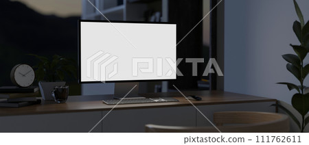 A modern dark home office at night with a computer mockup and decor on a minimal wooden table. A modern dark home office at night with a computer mockup and decor on a minimal wooden table. 111762611