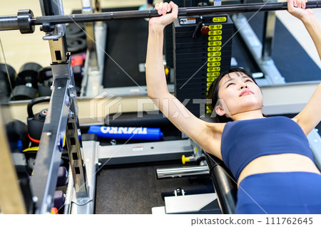 Woman training her body at the gym, barbell bench press, muscle training girl, workout clearly 111762645