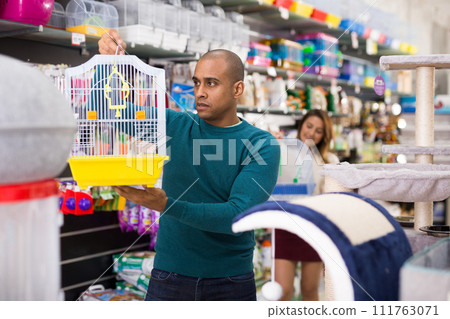 Man choosing cage for bird in shop Man choosing cage for bird in shop 111763071