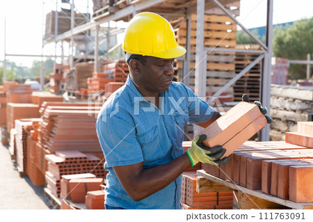 Male builder carrying bricks in outdoor warehouse 111763091