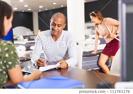 manager of furniture salon invites man to sign a payment document 111763176