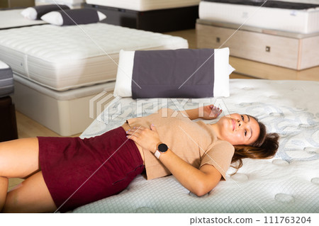 Young latin american woman lying on bed in furniture store Young latin american woman lying on bed in furniture store 111763204