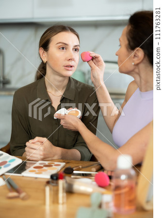 Makeup artist applying foundation to woman face using sponge Makeup artist applying foundation to woman face using sponge 111763281