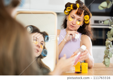 Two women curl their hair with curlers and use patches Two women curl their hair with curlers and use patches 111763316