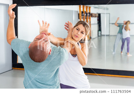 Strong cheerful woman is training with man on the self-defense course 111763504
