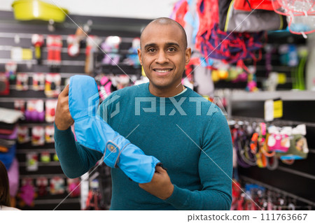 Man choosing clothes for dog in shop Man choosing clothes for dog in shop 111763667