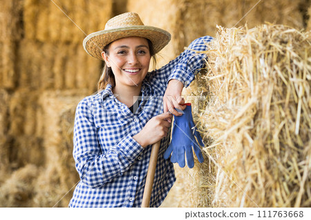 Female farmer posing in barn against the backdrop of hay bales Female farmer posing in barn against the backdrop of hay bales 111763668