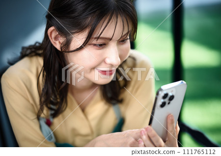 在房間裡操作智慧型手機的家庭主婦 在房間裡操作智慧型手機的家庭主婦 111765112