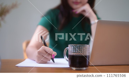 Young asian student women using technology laptop to studying and watching lecture webinar in online class while writing information in notebook and learning knowledge remote education from home 111765506