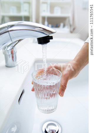 pour tap water into a glass pour tap water into a glass 111765541