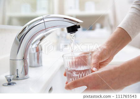 pour tap water into a glass 111765543