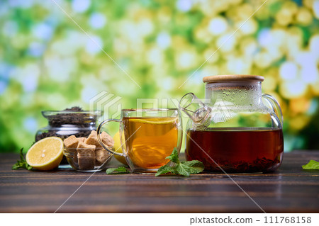 natural organic herbal tea in glass teapot and cup on a wooden table natural organic herbal tea in glass teapot and cup on a wooden table 111768158