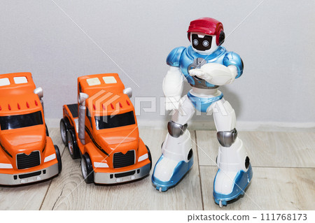 on the floor there are children's toy cars made of plastic and a robot 111768173