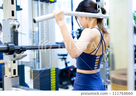 Woman training her body at the gym, lat pulldown, muscle training girl's back workout Woman training her body at the gym, lat pulldown, muscle training girl's back workout 111768660