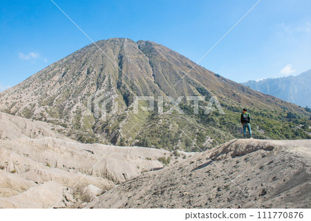Tourist standing at the ridge in front of Mount Batok volcano in Bromo Tengger Semeru National Park in East Java, Indonesia. 111770876