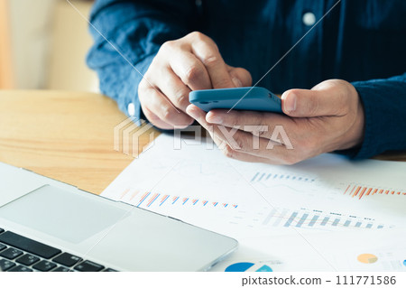 Hands of a man operating a computer and smartphone 111771586