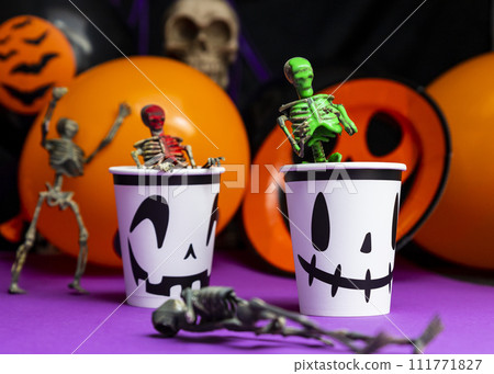 Halloween party. Skeletons coming out from the cup with balloons and skull in the background 111771827