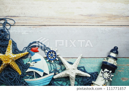 Nautical theme background with sail boat Starfish and blue fishing net on wooden background Nautical theme background with sail boat Starfish and blue fishing net on wooden background 111771857