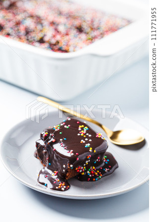 Piece of classic chocolate cake with colored sprinkles. Piece of classic chocolate cake with colored sprinkles. 111771955