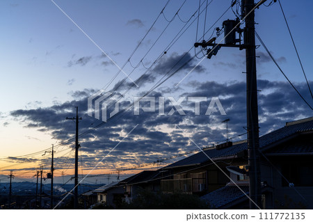 早春的夕陽天空照亮了住宅區,金色的天空漂浮著晚霞,藍天的漸變,黃昏的城市景觀 早春的夕陽天空照亮了住宅區,金色的天空漂浮著晚霞,藍天的漸變,黃昏的城市景觀 111772135