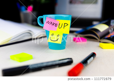 Sticky notes on a coffe cup at office desk. Wake up and smile. Begin your day with Positive thoughts 111772879
