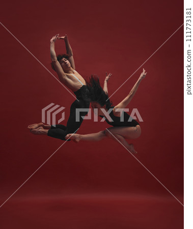 Young man and woman, ballet dancers making creative, beautiful performance, dancing against red background Young man and woman, ballet dancers making creative, beautiful performance, dancing against red background 111773181