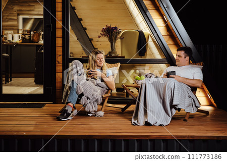 Couple sitting on the terrace in the evening and talking Couple sitting on the terrace in the evening and talking 111773186