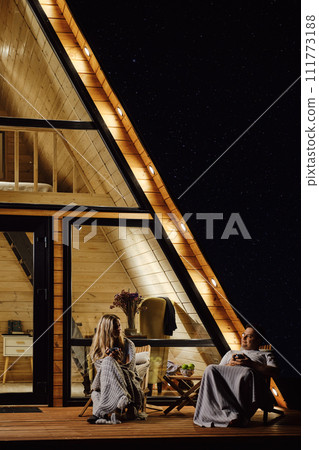 A friendly couple chats on the terrace in the evening A friendly couple chats on the terrace in the evening 111773188