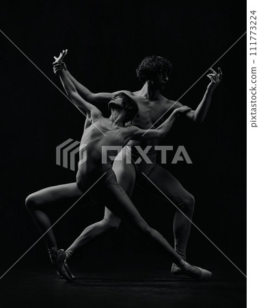 Dynamic artistic pose. Young man and woman, ballet dancers making creative, passionate performance. Black and white 111773224