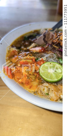 Indonesian style beef noodle soup called soto mie, freshly made soup with vermicelli rice noodle, fried shallots, chilli paste, and fried rissoles 111773951