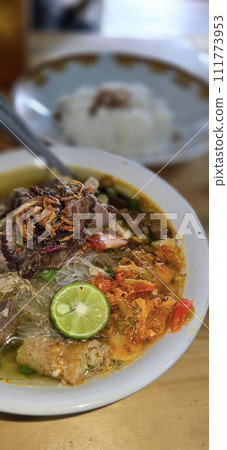 Indonesian style beef noodle soup called soto mie, freshly made soup with vermicelli rice noodle, fried shallots, chilli paste, and fried rissoles 111773953