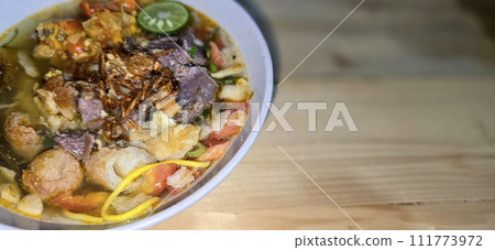 Indonesian style beef noodle soup called soto mie, freshly made soup with vermicelli rice noodle, fried shallots, chilli paste, and fried rissoles 111773972