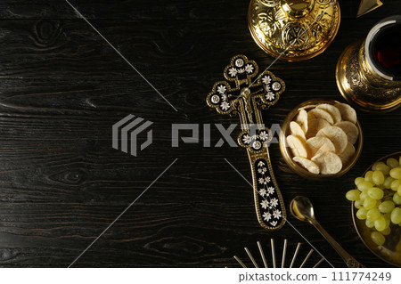 Cup with wine, grapes, bread and cross on dark wooden background, space for text Cup with wine, grapes, bread and cross on dark wooden background, space for text 111774249