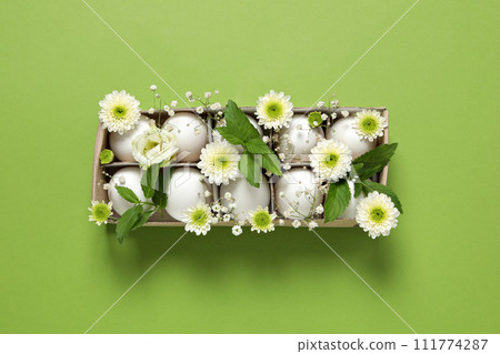 Chicken eggs in a green cardboard package with flowers. 111774287