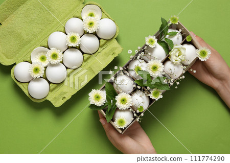 Chicken eggs in a green cardboard package with flowers. 111774290