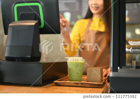 Female waitress standing at counter using cash register to accepting customer payments in coffee shop 111775382